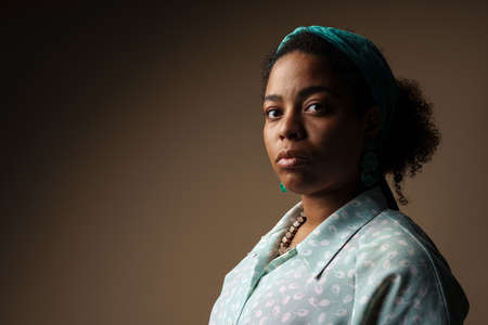Young black woman in headband posing and looking at camera isolated over grey backgroundの写真素材