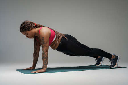 Young black woman doing exercise during yoga practice isolated over grey background