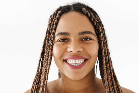 Smiling young african woman with dreadlocks over white wall background looking at cameraの写真素材