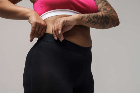 Proud young african bodypositive fitness woman over gray wall background