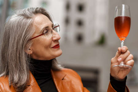 Grey white senior woman drinking wine while sitting in cafe outdoorsの写真素材