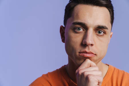 Young brunette man posing and looking at camera isolated over purple background