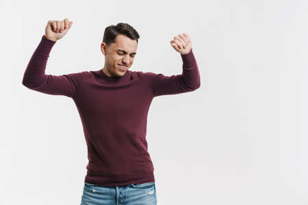Young brunette man smiling and dancing on camera isolated over white background