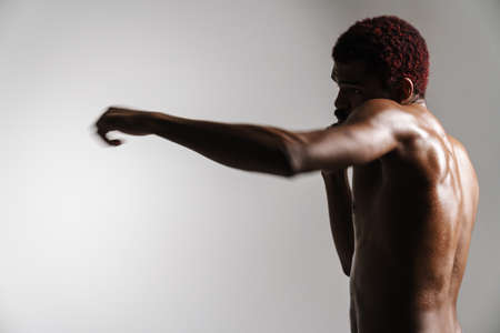 Black shirtless sportsman doing exercise while working out isolated over white backgroundの写真素材