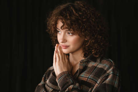 Smiling young redhead woman in plaid shirt standing in studio posing close up