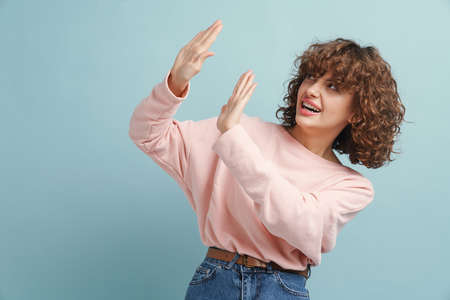 Ginger young woman looking aside and showing stop gesture isolated over white backgroundの写真素材
