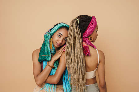 Young black two women hugging while posing on camera isolated over beige backgroundの写真素材