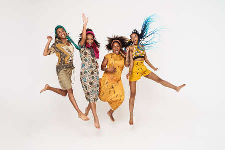 Young black four women jumping while making fun together isolated over white backgroundの写真素材