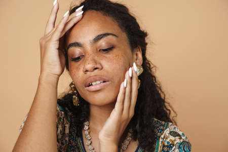Young black woman wearing dress posing on camera isolated over beige backgroundの写真素材