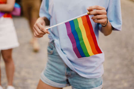 White woman holding rainbow flag during pride parade at city streetの写真素材