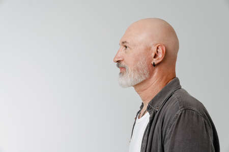 Bald european man with beard looking aside while posing in profile isolated over white backgroundの写真素材