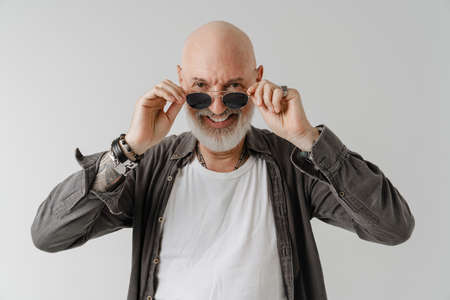 Bald european man in sunglasses laughing and looking at camera isolated over white backgroundの写真素材
