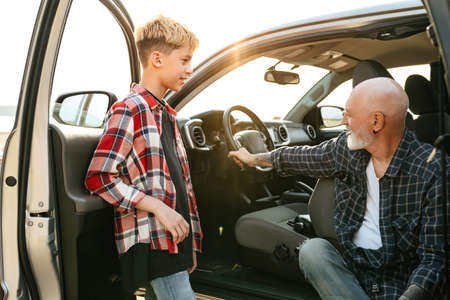 Smiling father and his son sitting inside a car at the beach talking