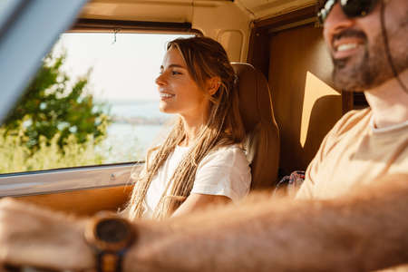 White happy couple smiling while driving trailer on summer dayの写真素材