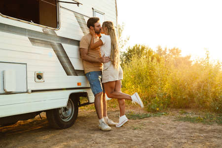 White couple hugging and kissing while standing by trailer outdoorsの写真素材