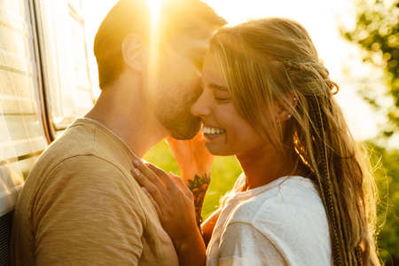 White couple hugging and smiling while standing by trailer outdoors