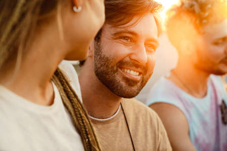 White couple hugging and smiling during picnic with their friends outdoorsの写真素材