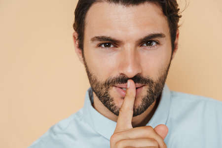 White bristle man wearing shirt showing silence gesture isolated over beige backgroundの写真素材