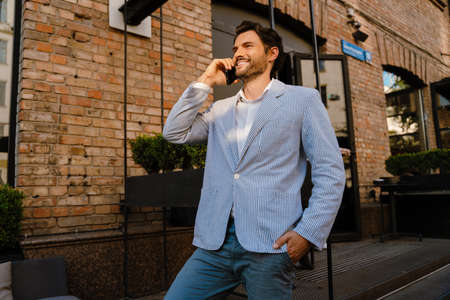 Young man smiling and talking on mobile phone while standing outdoors