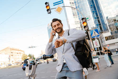 Young man talking on cellphone while sitting on bicycle on city street