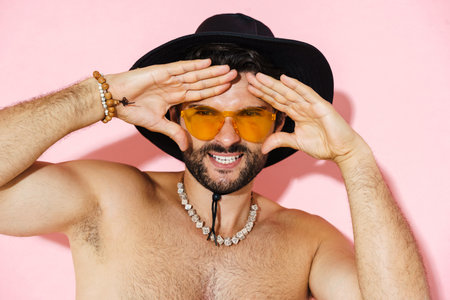 Young shirtless man wearing shorts gesturing and looking at camera isolated over pink backgroundの写真素材