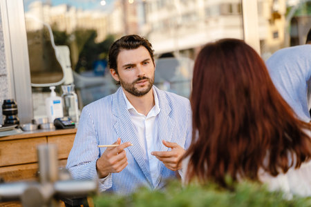 Young man and woman talking during business meeting at cafe outdoorsの写真素材