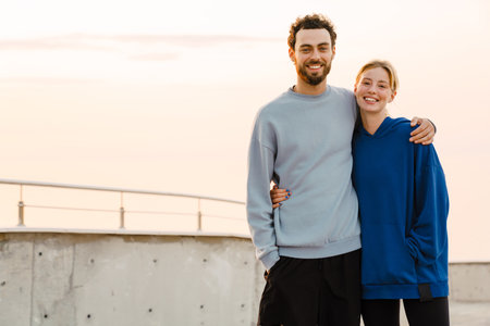 Young man and woman hugging while working out together on parking outdoorsの写真素材