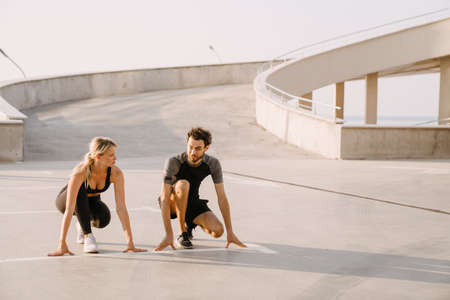 Young runners doing exercise while working out together on parking outdoorsの写真素材