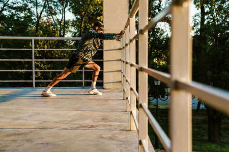 Young sportsman doing exercise while working out by railings outdoorsの写真素材