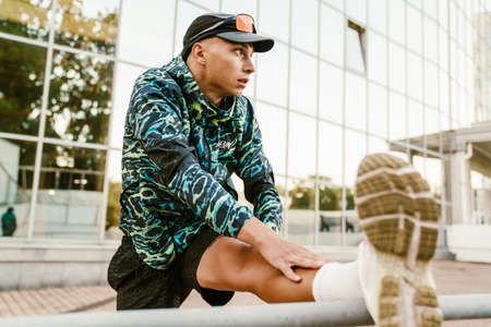 Young sportsman doing exercise while working out by building outdoors