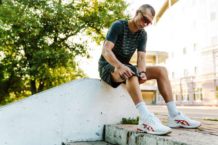 Young white runner in sportswear fixing bandage during workout outdoorsの写真素材
