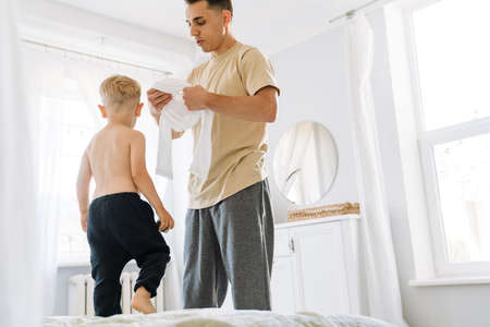 White man dressing his son while they spending time together at homeの写真素材