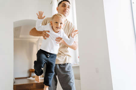 Young white father making fun and playing with his son at homeの写真素材