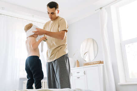 White man dressing his son while they spending time together at home