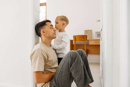 White boy drawing on doorjamb while measuring his father's height at homeの写真素材