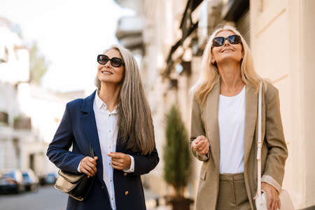Mature multiracial women smiling and talking while walking at city streetの写真素材