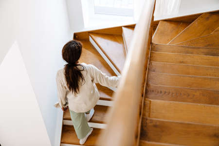 Young black woman wearing pajama walking upstairs at home