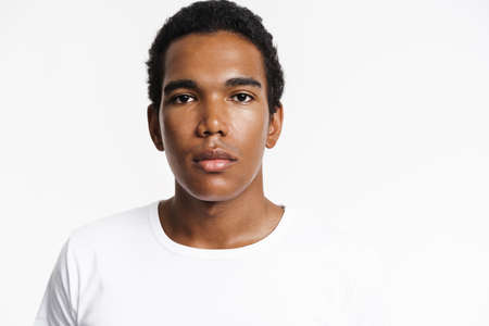Young black man dressed t-shirt posing and looking at camera isolated over white wallの写真素材