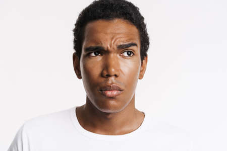 Young black man dressed t-shirt looking aside and frowning isolated over white wallの写真素材