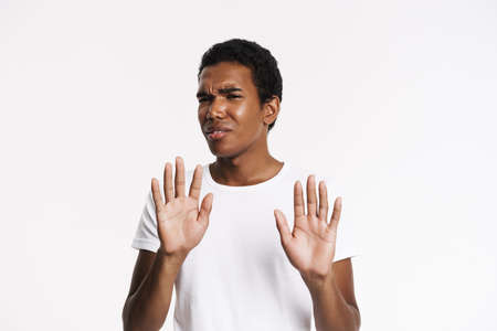 Young black man frowning while making stop gesture isolated over white backgroundの写真素材