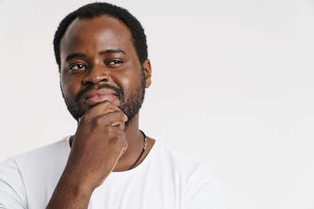 Black bristle man smiling while holding his chin isolated over white background