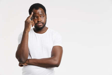 Black man dressed in t-shirt rubbing his temple and looking at camera isolated over white background