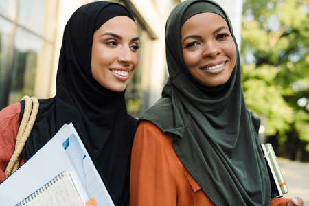 Multiracial muslim two women smiling together while standing outdoorsの写真素材