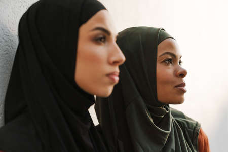 Multiracial muslim women posing and looking aside together outdoorsの写真素材