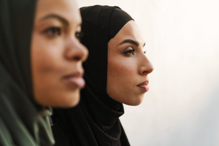 Multiracial muslim women posing and looking aside together outdoorsの写真素材