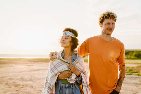 Young multiracial couple hugging and smiling while walking together outdoors