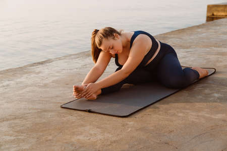 Ginger young woman doing exercise during yoga practice outdoorsの写真素材