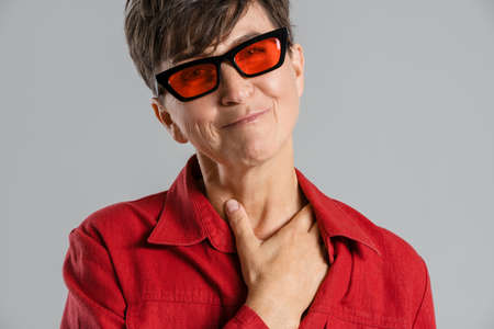 Mature european woman wearing sunglasses smiling at camera isolated over grey background