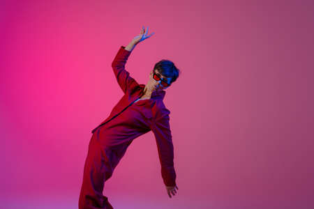 Mature european woman wearing sunglasses dancing on camera isolated over pink background