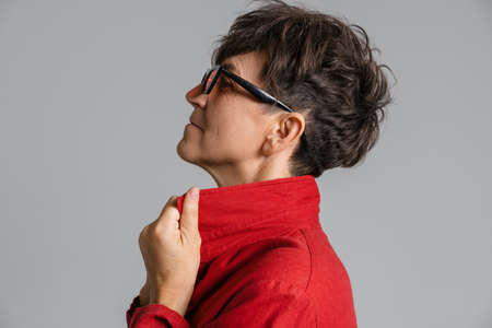 Mature european woman wearing sunglasses looking aside isolated over grey background
